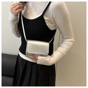 Detail of a metallic silver mini square crossbody bag on a model with a slim shoulder strap