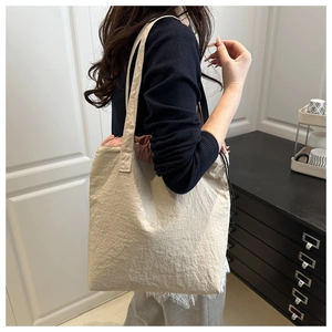 Close-up of pleated white bucket bag with pink drawstring lining on model's shoulder
