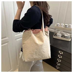 Detail of beige pleated tote bag featuring a pink drawstring lining and large capacity