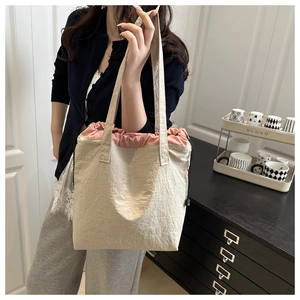 Detail of cream drawstring tote bag with pink lining and textured fabric finish