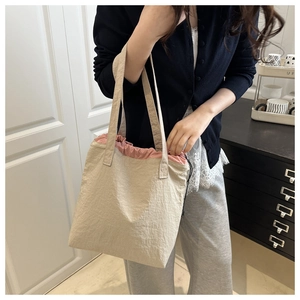 Close-up of khakhi shoulder tote with pink drawstring closure on a casual model