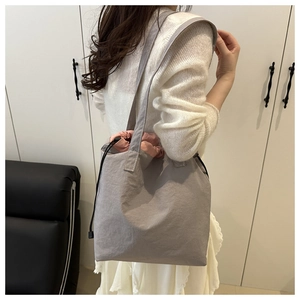 Detail view of large grey tote bag with pink drawstring lining shown on shoulder