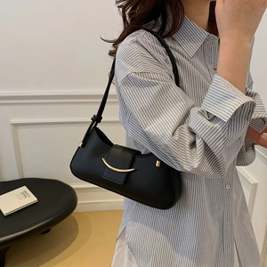 Elegant black leather underarm bag with gold crescent hardware and knotted strap on model