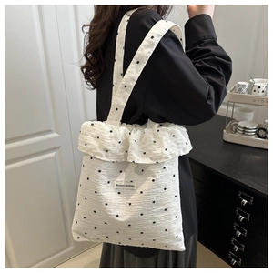 Detailed view of white chiffon tote bag featuring black polka dots and ruffled edges