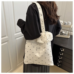 Detailed close-up of white ruffled canvas tote with black floral patterns and logo