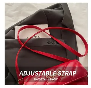Détail d'un sac en cuir matelassé rouge avec fermoir nœud doré sur un blazer gris foncé