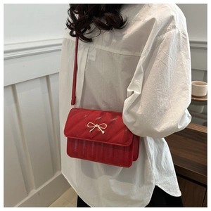 Détail du sac bandoulière rouge matelassé avec nœud en métal doré et coutures élégantes