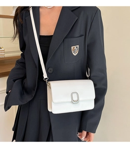 Detail of white leather crossbody bag with silver oval metallic twist lock closure