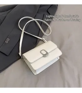 Close-up of a white rectangular crossbody bag with a silver oval metal buckle detail