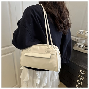 Detail einer cremeweißen PU-Leder-Schultertasche mit Seitentasche an einem Modell
