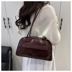 Detailansicht der weinroten Lackleder-Hobo-Tasche am Modell für den Büro-Look