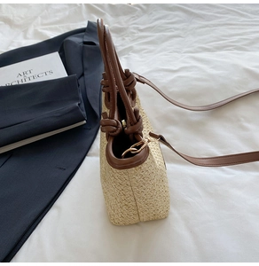 Dettaglio borsa a secchiello in paglia con manico a nodo in pelle marrone e tracolla elegante