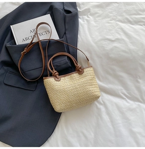 Borsa a mano in paglia intrecciata con manici in pelle marrone su fondo bianco