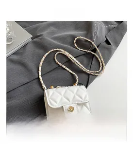 Detail of white quilted crossbody bag with a golden floral clasp on a textured suit jacket