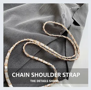 Detailed close-up of white leather interwoven with a gold metal chain strap on a blazer