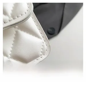 Detailed macro view of white quilted leather texture with premium stitching on small bag
