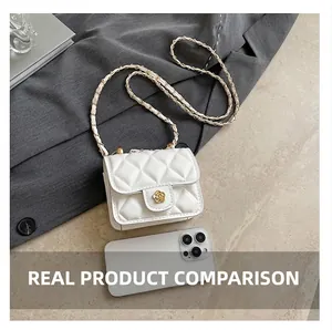 Mini quilted white crossbody bag with golden camellia buckle next to a smartphone
