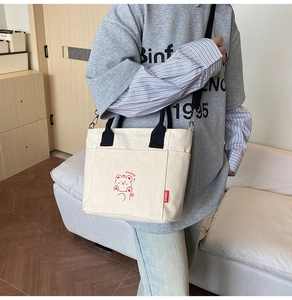 Detailed view of cream canvas tote bag featuring cute red bear print and black straps