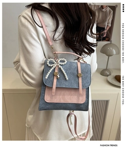 Detail view of a grey and pink contrast backpack featuring a pearl bow pendant accessory
