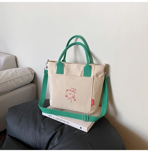 Detail of canvas bucket bag showing cute bear print and contrasting green handles