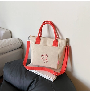 Detail of canvas bucket bag with red handles and cute bear illustration with Yummy text
