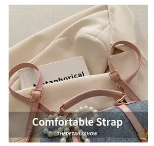 Detail of blue denim crossbody bag with pink leather trim and elegant pearl handle