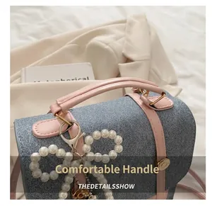 Detailed close-up of blue denim and pink leather bag with a pearl bow charm and gold hardware