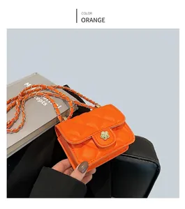 Détail du mini sac orange avec matelassage en losange et boucle camélia dorée élégante