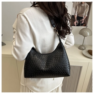 Detail of black woven leather shoulder bag showing intricate texture and crescent shape