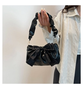 Gros plan d'un sac à bandoulière plissé noir brillant avec un grand nœud décoratif