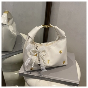 Detalle de bolso de PU blanco crema con herrajes dorados, encaje de perlas y remaches