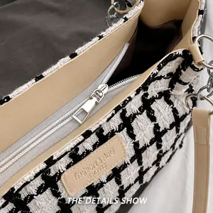 Detailaufnahme des glatten silbernen Reißverschlusses an einer schwarz-weißen Tweed-Tasche