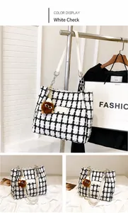 Detail of white checkered tweed tote bag with leather strap and plush charm