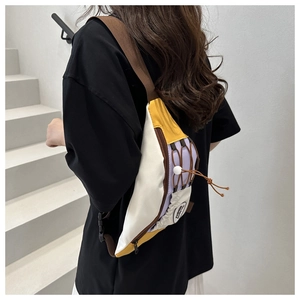 Détail du sac bandoulière color-block blanc, jaune et violet porté par un mannequin