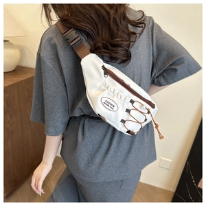 Détail du sac bandoulière blanc en nylon avec sangle réglable marron porté par le mannequin