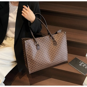 Close-up of brown monogram tote bag with sturdy metal feet and leather texture details