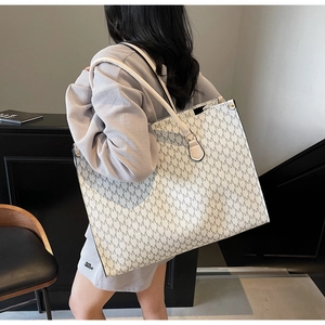 Detail of white tote bag with gray M-letter print and black trim shown on model shoulder