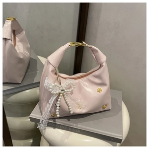 Détail du sac hobo rose brillant avec nœud en dentelle blanche et perles élégantes