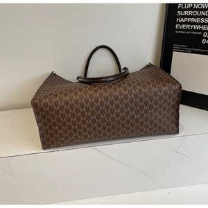 Detail of large brown tote bag featuring vintage M-letter print and round top handles