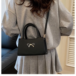 Détail du sac à main en cuir PU noir orné d'un fermoir en métal doré en forme de nœud élégant
