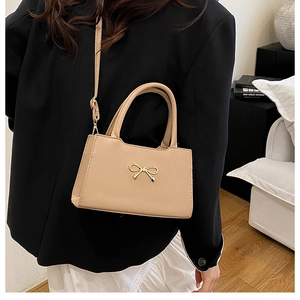 Détail du sac crème avec boucle nœud dorée et cuir PU à texture fine élégante