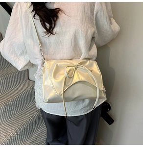 Détail du sac carré beige nacré avec un élégant nœud papillon sur le côté