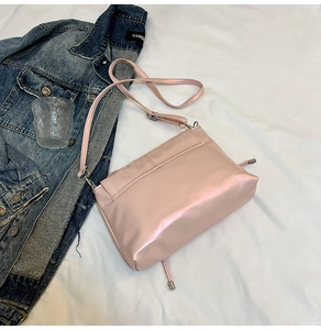 Pink bow square crossbody bag with pearly finish on white fabric and denim prop