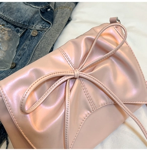 Gros plan sur un sac bandoulière rose perlé avec un grand nœud et des coutures précises