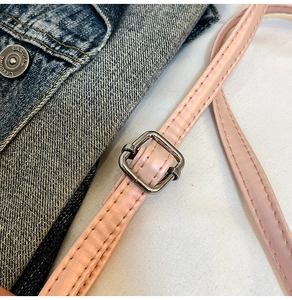Détail de la bandoulière en similicuir rose avec boucle en métal argenté et surpiqûres