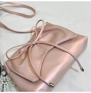 Détail du sac bandoulière rose avec nœud et pendentif élégant en perles blanches