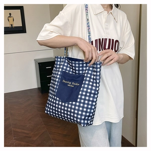 Detail of blue checkerboard canvas tote bag with front pocket and woven strap