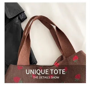 Detailed close-up of brown corduroy tote bag with strawberry prints and canvas handle