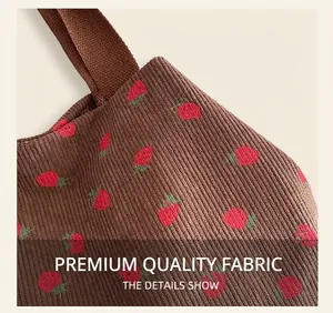 Detail showing high-quality corduroy fabric texture and red strawberry print on tote bag