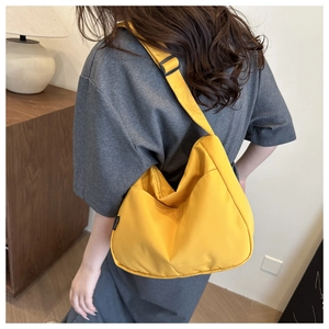 Seitenansicht einer gelben Halbmondtasche aus Nylon, getragen von einem Modell zu Hause